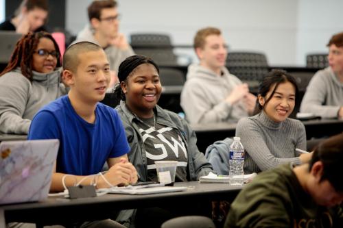 Students in a Statistics classroom listening to a lecture and smiling 